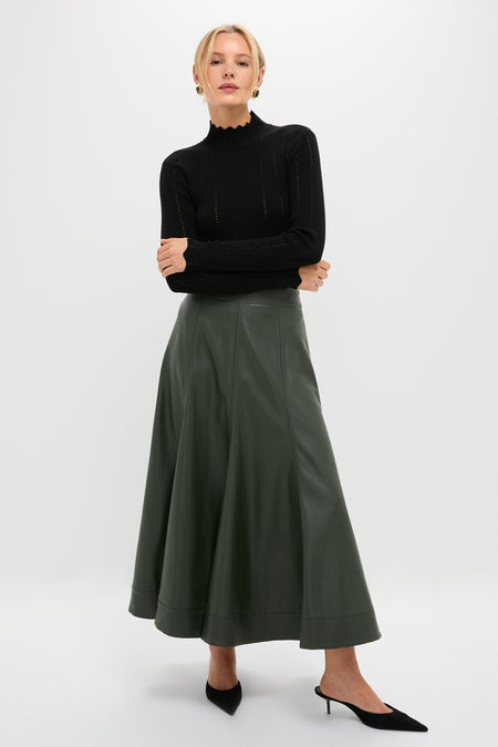 Woman models Black Pointelle Knit Allen Turtleneck with scalloped neck, paired with a high-waisted flared skirt and mules, showcasing an effortlessly classic and high-end look.