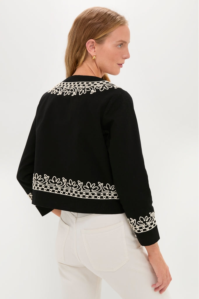Woman wearing the Soutache Cotton Maddy Jacket, showcasing classic, effortless style with intricate white embroidery on black fabric, paired with high-waisted pants for a fun, high-end look.