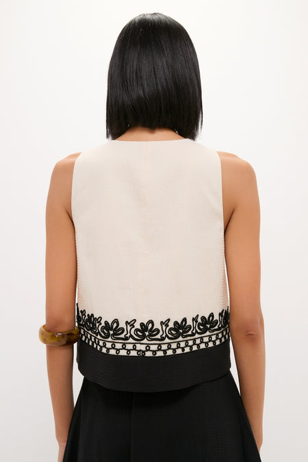 Back view of a woman wearing the classic, effortlessly chic Soutache Cotton June Top, featuring floral-vine embroidery, paired with black bottoms and an amber bangle.