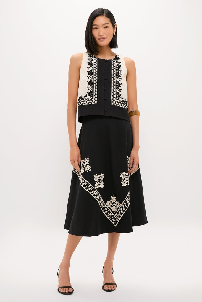Woman wearing the classic Soutache Cotton June Top, a sleeveless cropped vest with floral embroidery, paired with a high-waisted skirt, embodying effortless and high-end style.