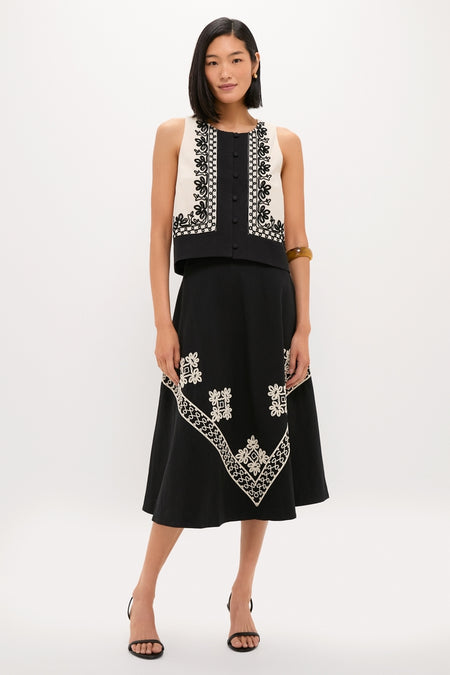 Woman wearing the classic Soutache Cotton June Top, a sleeveless cropped vest with floral embroidery, paired with a high-waisted skirt, embodying effortless and high-end style.