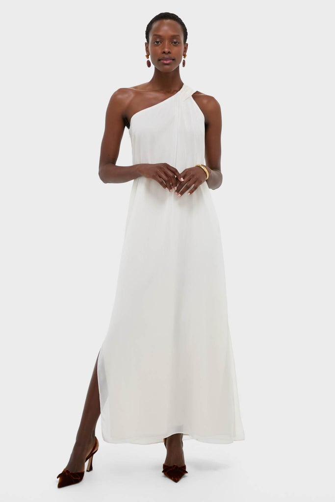 Woman modeling the classic, high-end Ivory Soleil Gown with an effortless one-shoulder design and side slit, styled with brown heels and elegant jewelry.