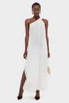 Woman modeling the Ivory Soleil Gown, a classic one-shoulder maxi dress with side slits, styled with elegant accessories for an effortless, high-end look.