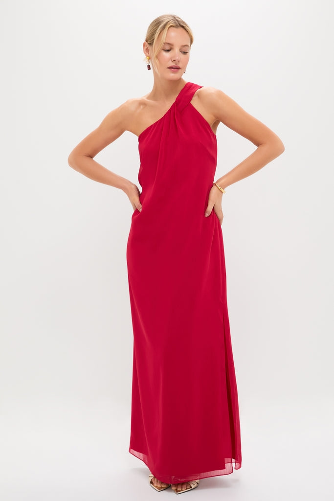 Woman modeling the Red Soleil Gown, a classic, high-end floor-length dress with an asymmetrical neckline and side slit, embodying effortless elegance and fun for wedding guests.