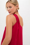 Rear view of woman in sleeveless, draped red Soleil gown, showcasing classic elegance and effortless style, accessorized with multicolored gemstone earring.