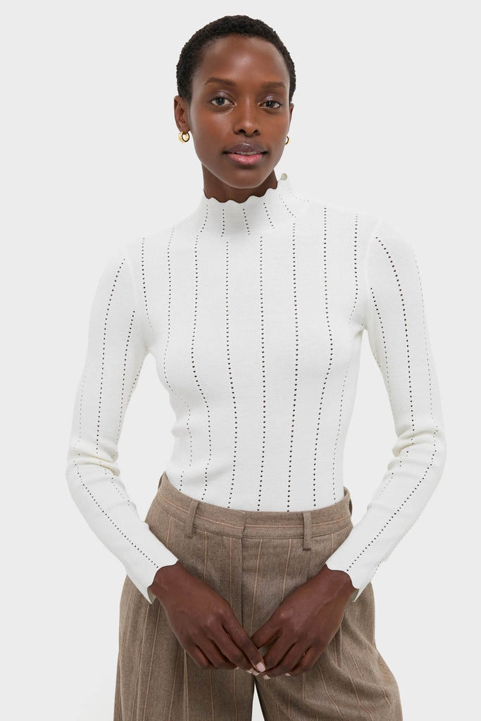 Black woman in a classic, effortless White Pointelle Knit Allen Turtleneck with eyelet stripes, paired with high-end, wide-leg trousers, embodying fun sophistication.