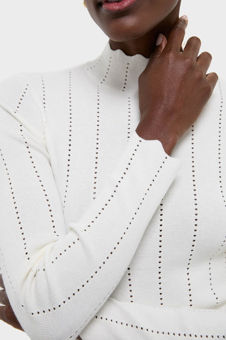 The White Pointelle Knit Allen Turtleneck features classic vertical eyelet stripes and a scalloped high neckline, offering an effortless, high-end style for a fun, confident look.