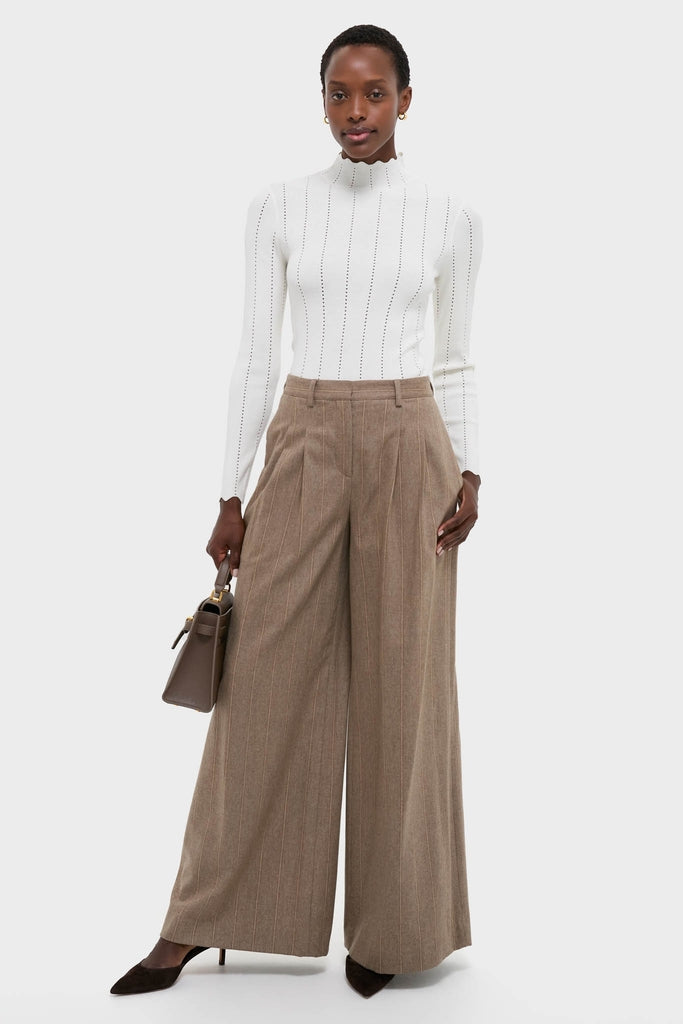 Model wearing the classic White Pointelle Knit Allen Turtleneck, featuring subtle vertical perforations and scalloped details, paired with high-end pin-striped trousers for an effortless, fun look.