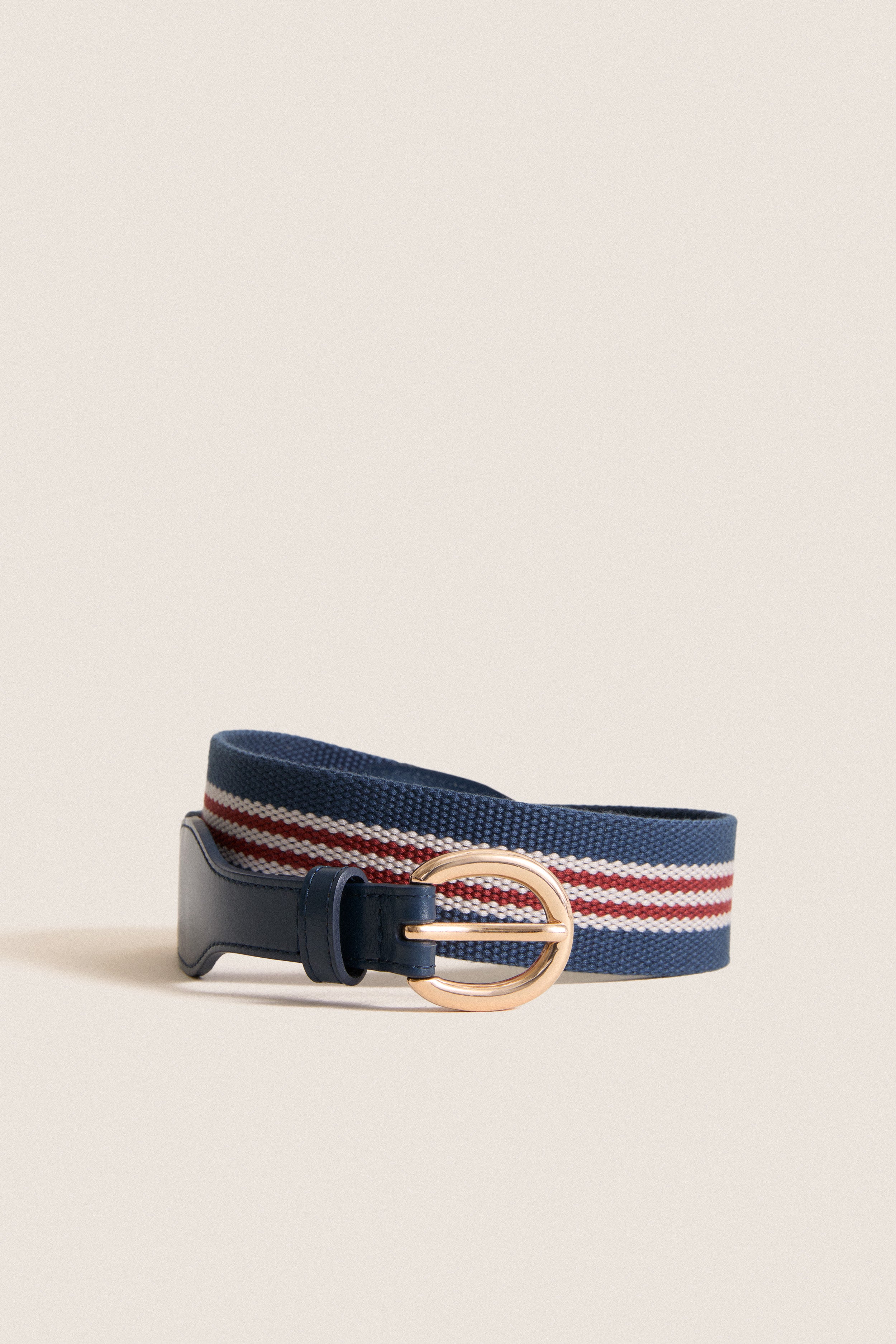 Navy and Red Woven Strap Belt with red-and-white stripes, polished gold buckle, and navy leather trim, offering a classic, effortless style for a fun, high-end look.