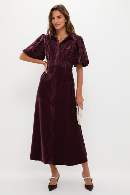 Model in Winetasting Velvet Lace Delaney Dress, showcasing a classic, effortless style with puff sleeves and embroidery, accessorized with a beaded clutch and heels for a high-end look.