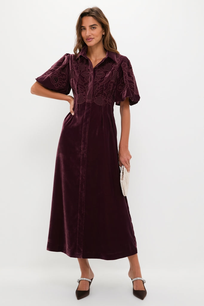 Model in Winetasting Velvet Lace Delaney Dress, showcasing a classic, effortless style with puff sleeves and embroidery, accessorized with a beaded clutch and heels for a high-end look.