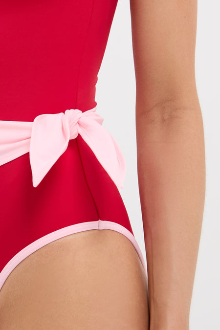 Poppy and Pink Cleo One Piece with Scarf features a classic red design, pale-pink trim, and a sash bow, offering an effortless, fun, high-end look.