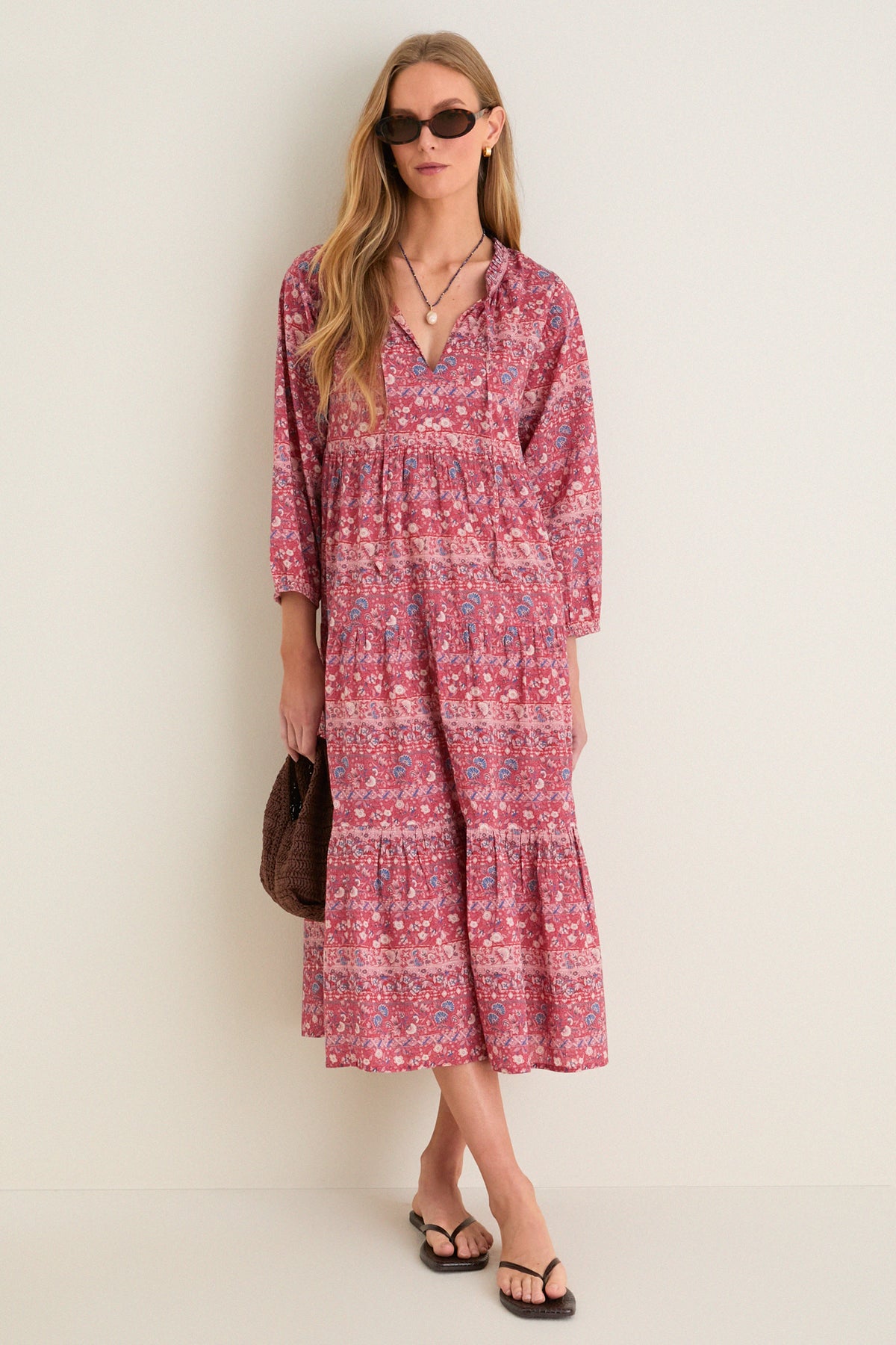 Model in classic Americana Batik Stripe Long Sleeve Salty Paloma Caftan, effortlessly styled with a brown woven handbag, sandals, necklace, and sunglasses, embodying bohemian elegance.
