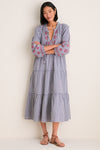 Woman in Navy Prism Embroidered Gingham Long Sleeve Salty Paloma Caftan, showcasing its classic, effortless design with tiered skirt and red embroidery, paired with brown leather sandals.