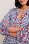 Woman in a classic, effortless Navy Prism Embroidered Gingham Long Sleeve Salty Paloma Caftan with ruffled neckline and embroidered details, embodying fun, high-end bohemian style.