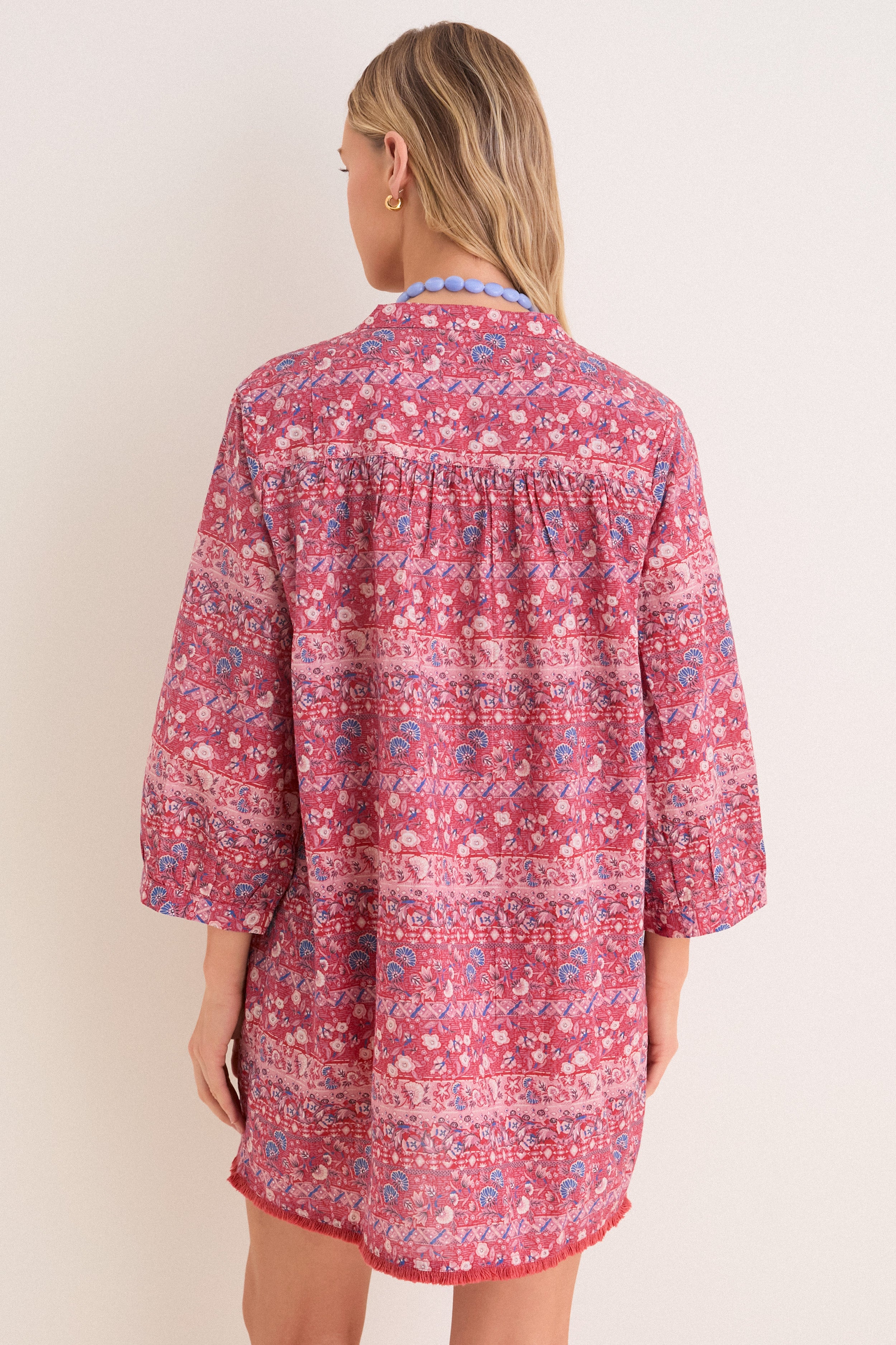 Classic back view of a woman in an effortless, high-end Americana Batik Stripe Bondi Coverup, featuring floral-geometric print and a chunky necklace. Fun and chic style.