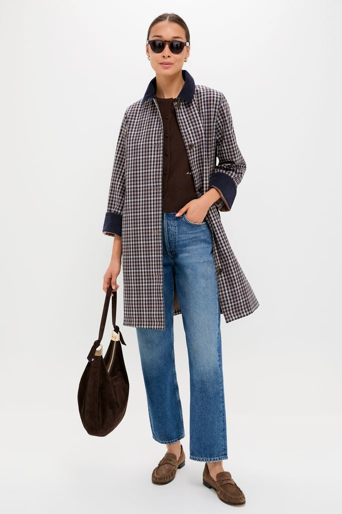 Woman in navy-and-tan checked overcoat wearing classic Bordeaux Leonard Sunglasses, embodying an effortless, high-end autumn style with fun, polished details. Holding a brown suede handbag.