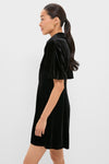 Model in profile wearing Black Velvet Mini Delaney Dress with puff sleeves and flared skirt, showcasing a classic and effortless high-end style.