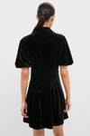 Woman in Black Velvet Mini Delaney Dress with puffed sleeves, showcasing its classic, effortless fit and high-end design from Tuckernuck, perfect for fun, versatile occasions.