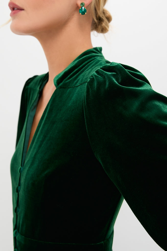 Woman in a classic, high-end Green Velvet Serena Dress with balloon sleeves and button placket, exuding effortless elegance. Paired with matching gemstone earrings for a fun, sophisticated look.