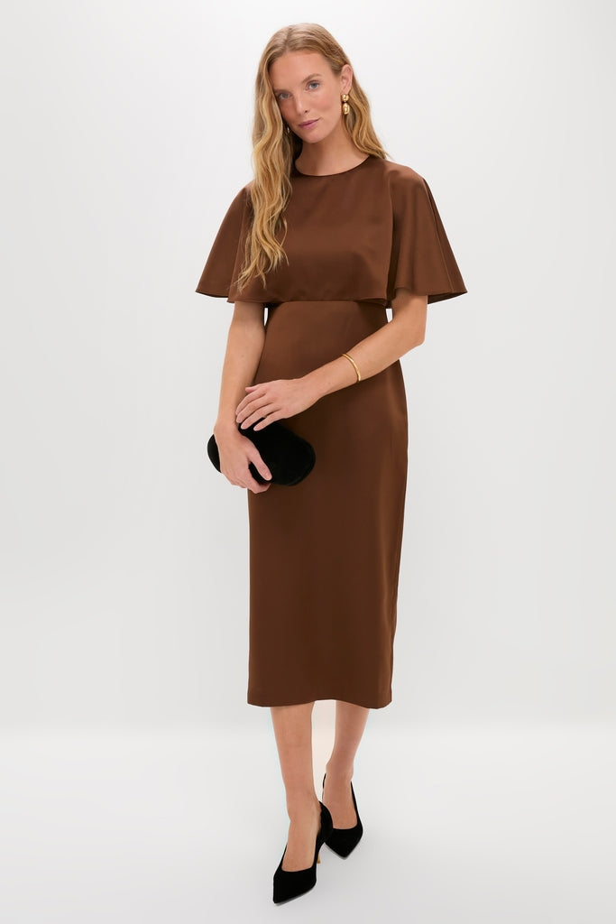 Model in Chocolate Brown Cape Leah Dress, flaunting classic, effortless style with cape sleeves, black velvet clutch, pointed pumps, and simple gold jewelry, embodying high-end, fun fashion.