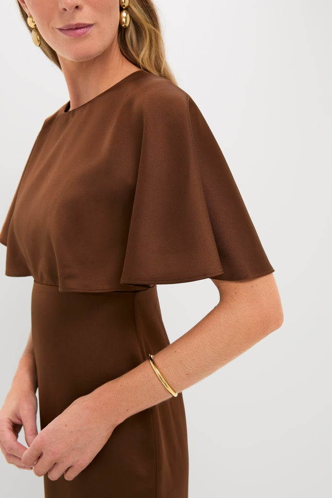 Chocolate Brown Cape Leah Dress with classic flutter sleeves, styled with chunky gold bangle and earrings. Effortless, high-end look exudes fun sophistication.