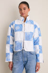Model in Blue and White Quilted Cropped Townley Jacket, featuring classic patchwork, paired with light-wash jeans and a gold necklace for an effortless, high-end look.