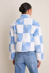 Back view of a person wearing the Blue and White Quilted Cropped Townley Jacket with high-waisted jeans, showcasing an effortless, high-end, and fun style.