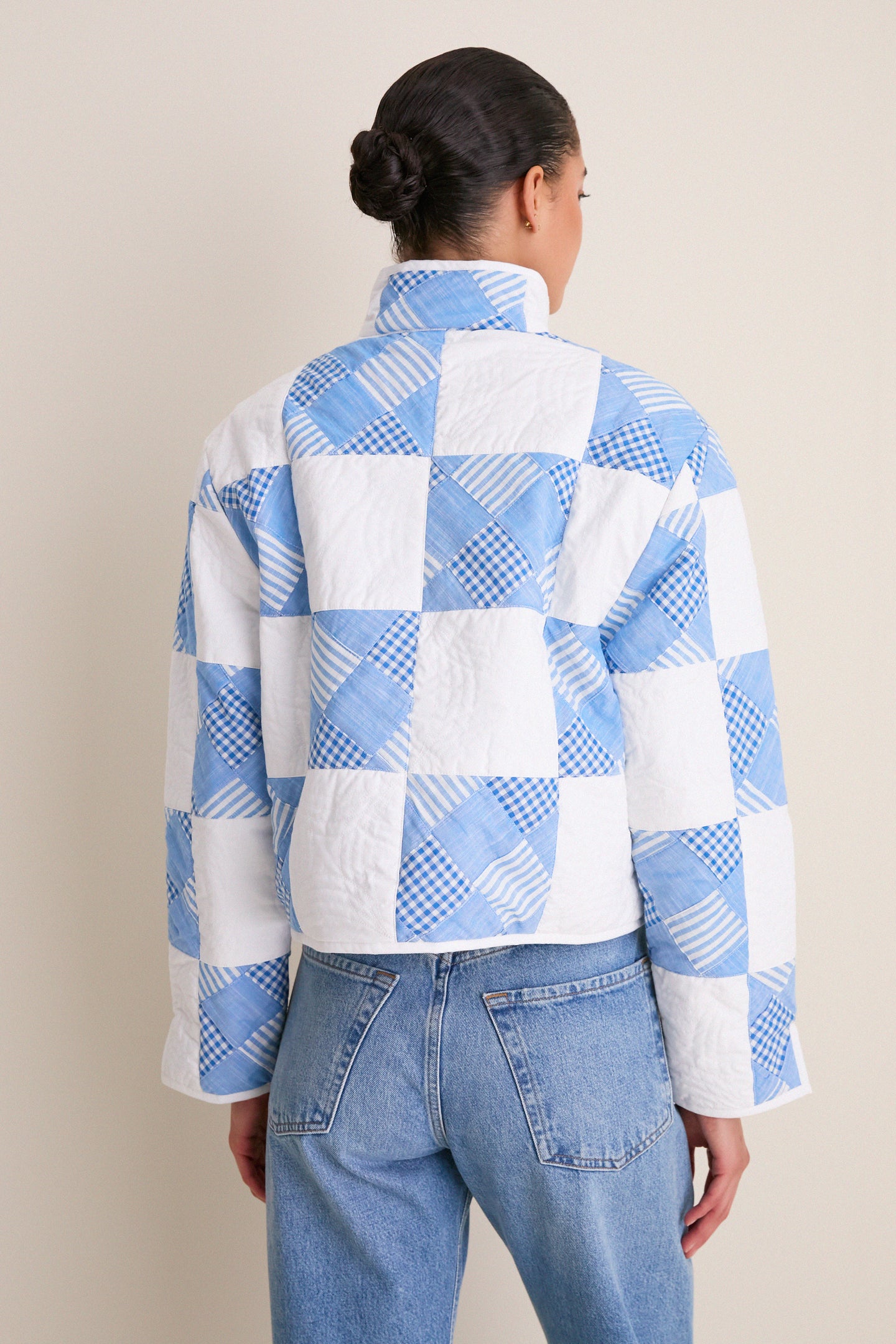 Back view of a person wearing the Blue and White Quilted Cropped Townley Jacket with high-waisted jeans, showcasing an effortless, high-end, and fun style.