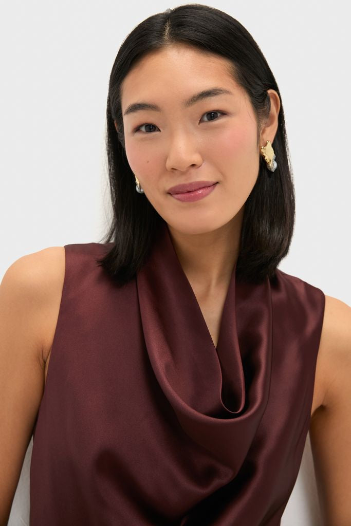 Young woman in a classic, high-end Chocolate Satin Sinclair Dress with sculptural earrings, showcasing the elegant cowl neck and effortless drape, embodying fun sophistication.