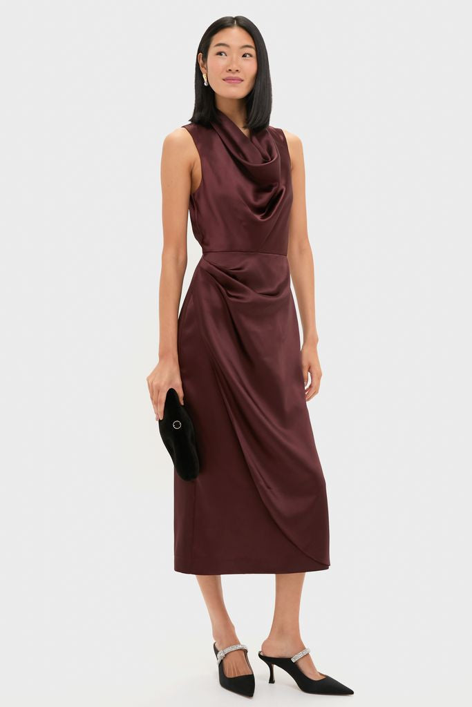Chocolate Satin Sinclair Dress on model; classic, effortless midi with cowl neck, subtle waist draping. Paired with black clutch and crystal-studded mules for a high-end, fun look.