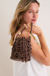 Woman holding the Mocha Swirl Bucket Bag, showcasing its classic macramé-like texture with twisted-rope handles, reflecting effortless style and high-end elegance.