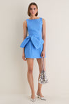 Blue Jacquard Briallen Bow Mini Dress with classic boat neckline and oversized bow, styled effortlessly with a sequined pouch and metallic sling-back heels for a fun, high-end look.