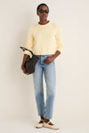 A person wearing the Sunshine and Cream Fine Stripe Mini Marina Sweater with light jeans and chic accessories, embodying a classic, effortless, high-end, and fun spring look.