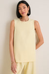 Woman wearing the classic Butter Maxime Top, an effortless sleeveless design with crewneck and side slits, paired with matching trousers, exuding fun and high-end elegance.