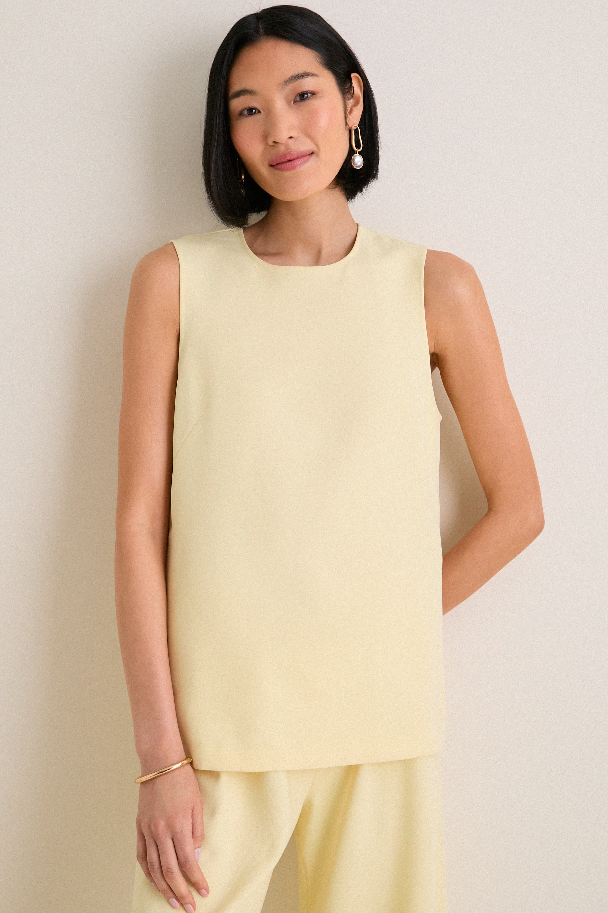 Woman wearing the classic Butter Maxime Top, an effortless sleeveless design with crewneck and side slits, paired with matching trousers, exuding fun and high-end elegance.