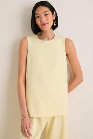 Woman wearing the classic Butter Maxime Top, an effortless sleeveless design with crewneck and side slits, paired with matching trousers, exuding fun and high-end elegance.