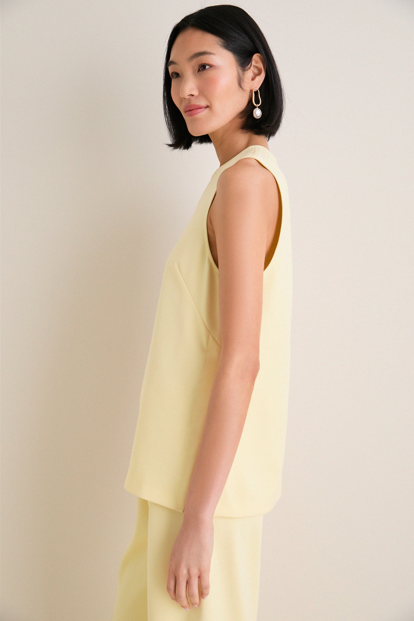 Model in profile wearing the classic, effortless Butter Maxime Top, featuring a crewneck and sleeveless design, paired with matching pants for a high-end, fun look.