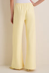 Model wearing classic Butter Crepe Colby Pant, high-waisted and wide-leg, paired with a white top and gold bangle, showcasing effortless, high-end style.