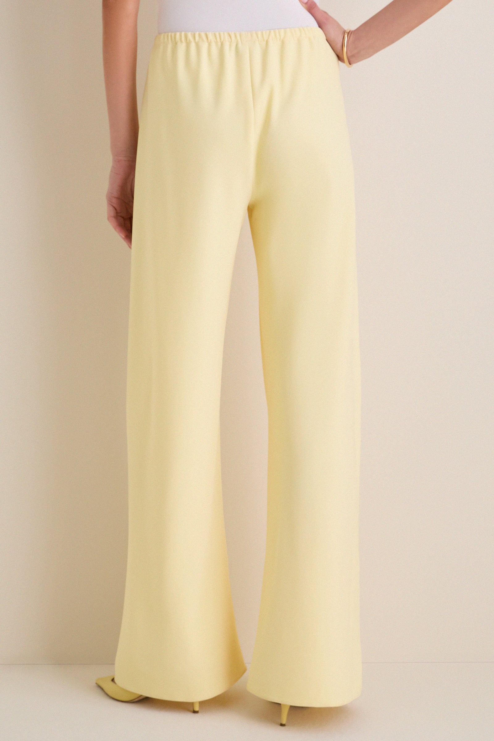 Model wearing classic Butter Crepe Colby Pant, high-waisted and wide-leg, paired with a white top and gold bangle, showcasing effortless, high-end style.