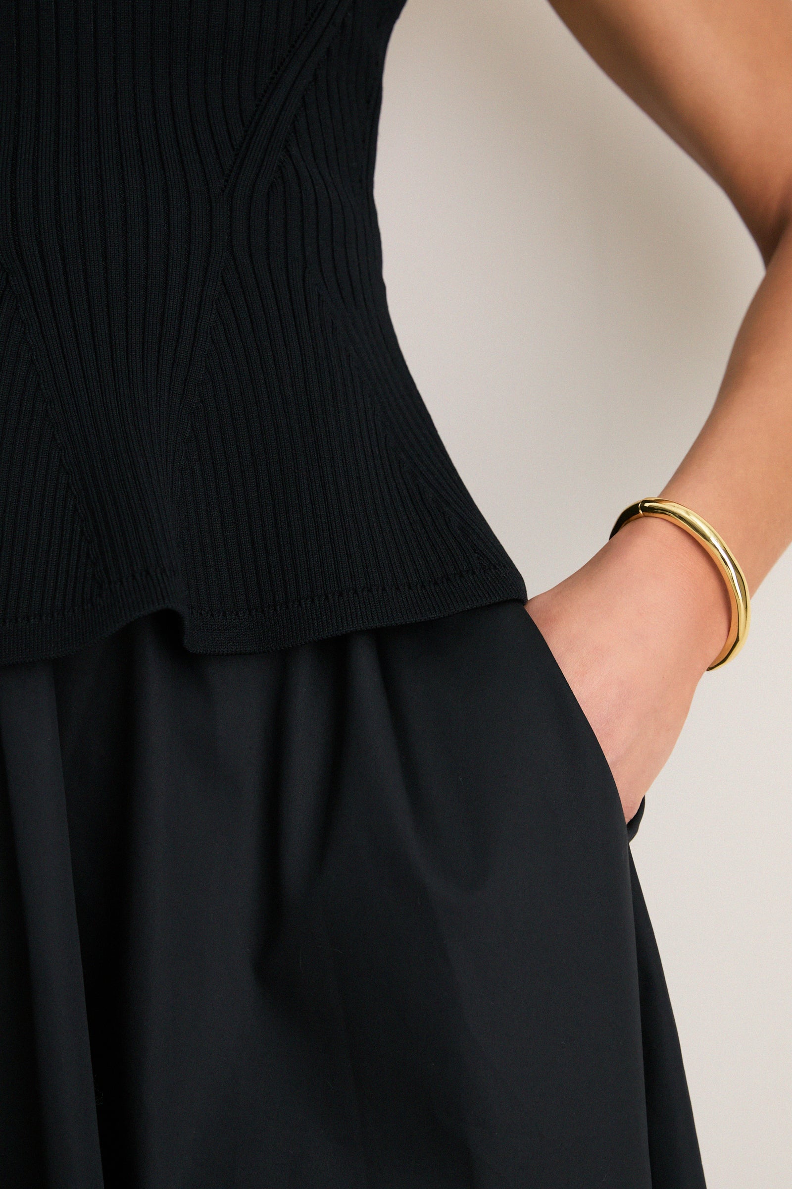 The Black Peplum Cara Dress, featuring a classic ribbed top with playful peplum hem and full skirt, embodies effortless, high-end style with a fun twist.