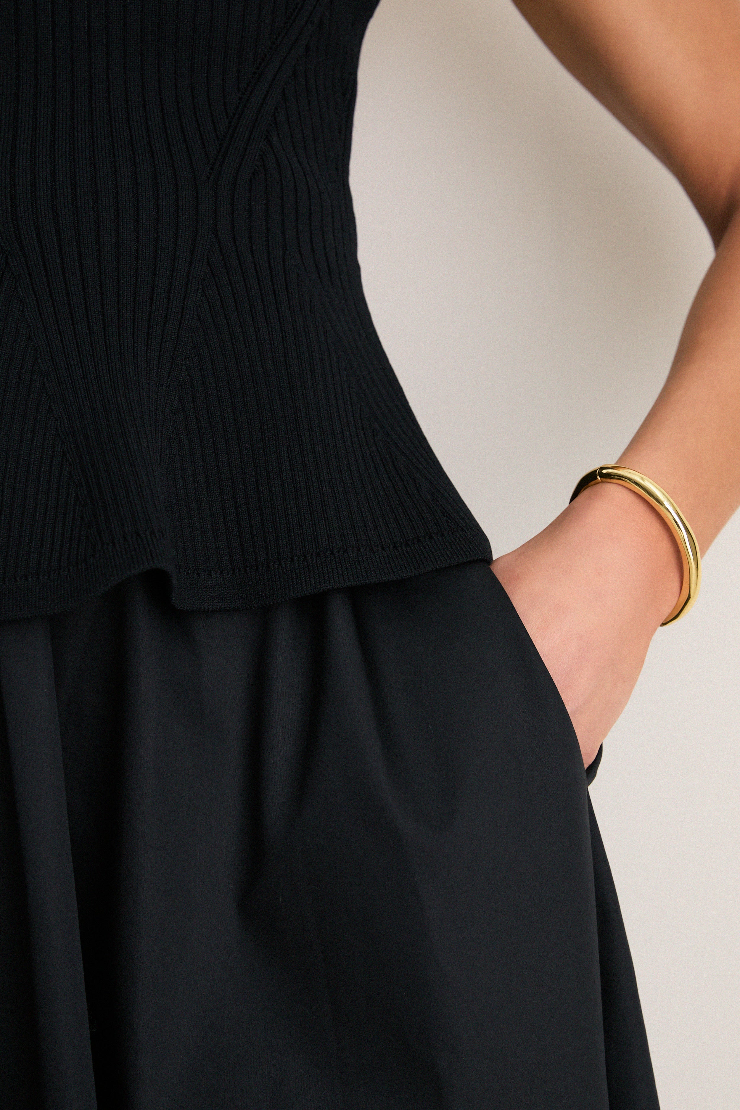 The Black Peplum Cara Dress, featuring a classic ribbed top with playful peplum hem and full skirt, embodies effortless, high-end style with a fun twist.