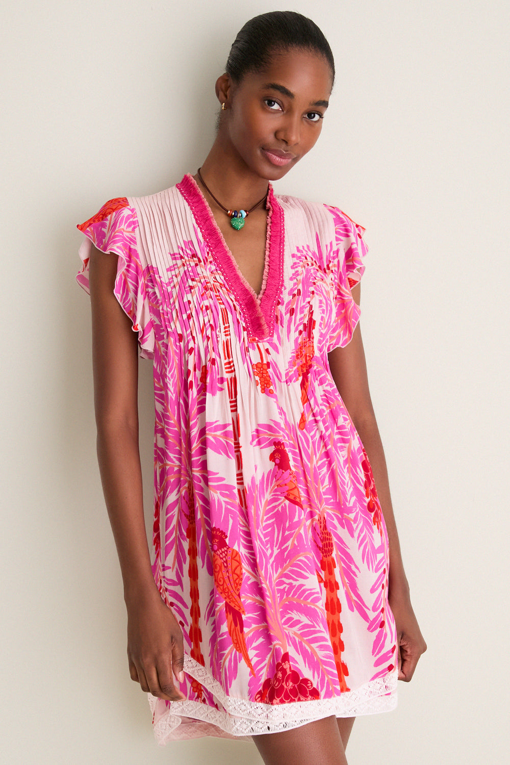 Woman wearing the Pink Holy Snake Mini Sasha Dress, a classic boho chic design featuring a fringed V-neck, flutter sleeves, and lace hem, exuding effortless, high-end fun.