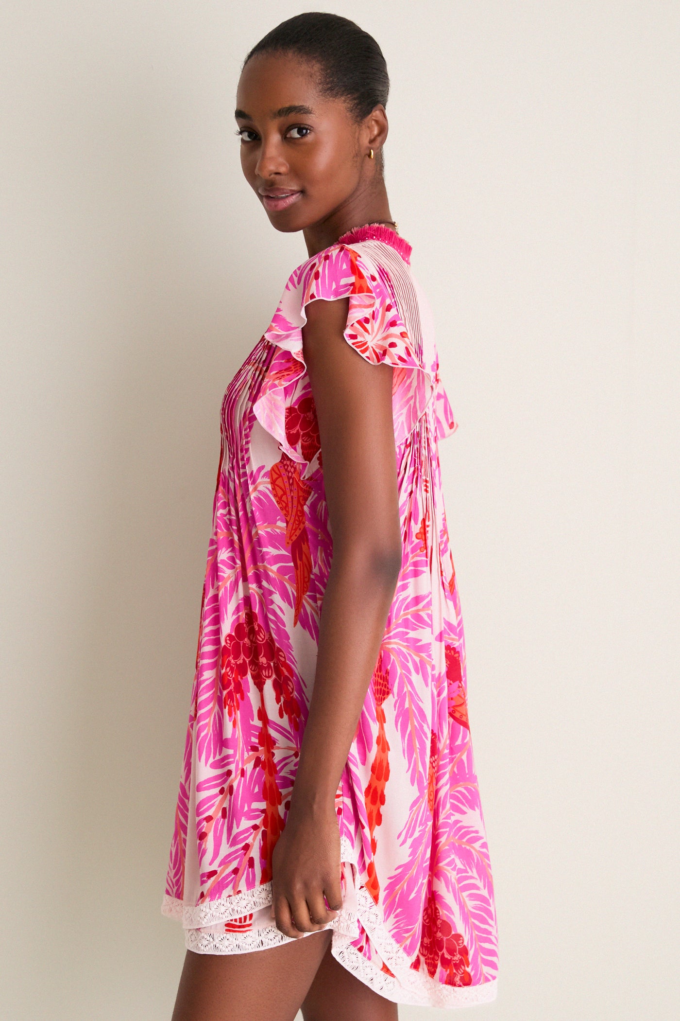 Young woman in profile wearing the Pink Holy Snake Mini Sasha Dress, showcasing a classic, effortless boho chic style with floral print and lace hem.
