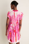 Back view of a woman in the Pink Holy Snake Mini Sasha Dress, featuring a classic, fun, tropical print with flutter sleeves, exuding effortless, high-end boho-chic style.