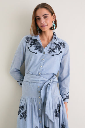 Young woman in The Chambray Embroidered Western Shirt featuring classic floral embroidery, pleated skirt, and relaxed fit, embodying effortless high-end style and fun confidence.
