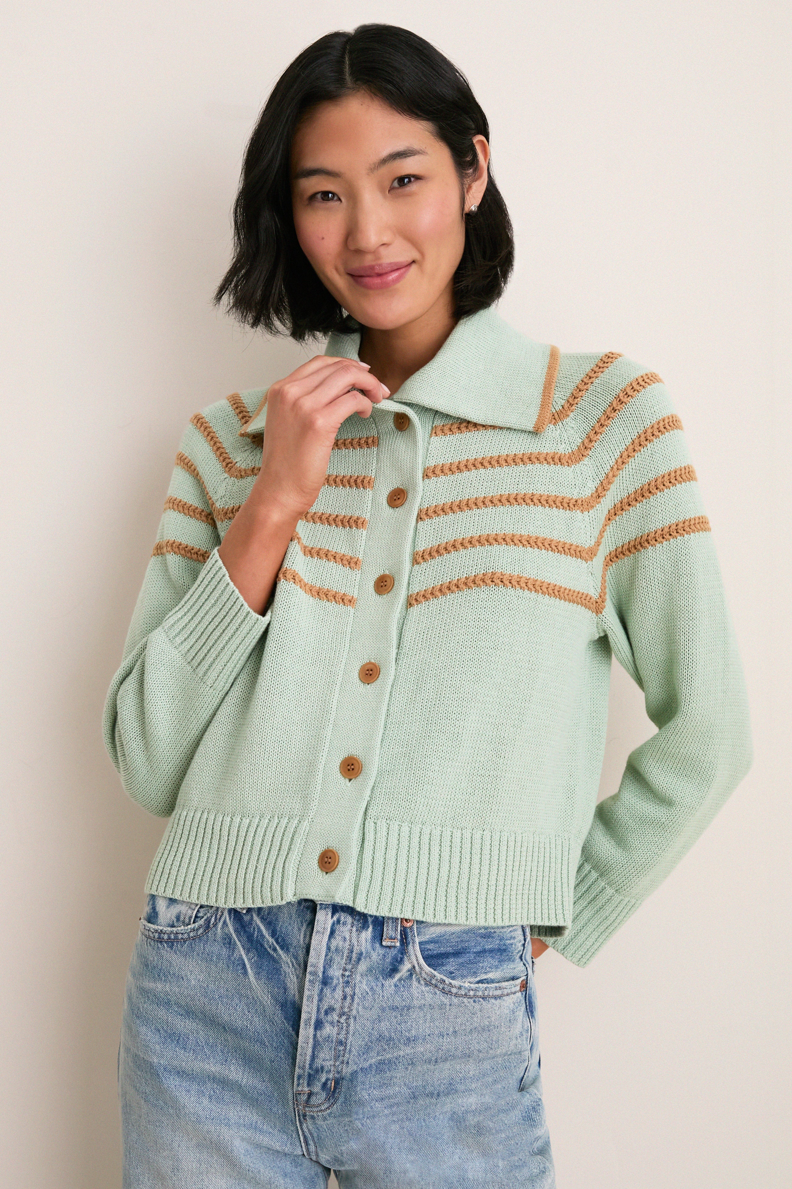 Young woman models the Seafoam Scholar Cardigan with Crochet Stripes, showcasing its classic, effortless style with fun, high-end details like Corozo buttons and textured knit.