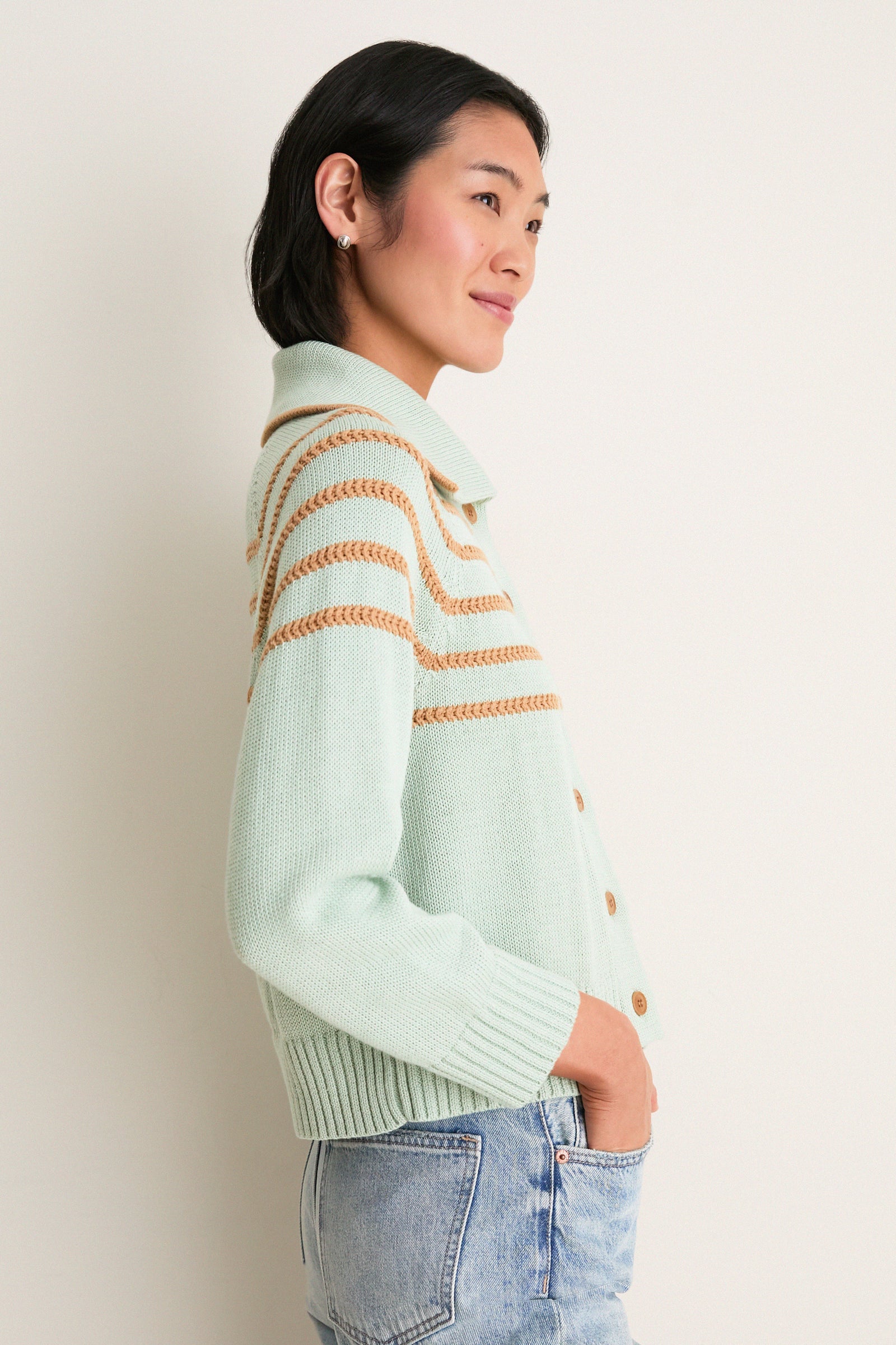 Young woman in profile wearing the Seafoam Scholar Cardigan with Crochet Stripes, showcasing its classic, effortless design with a fun, high-end vibe.