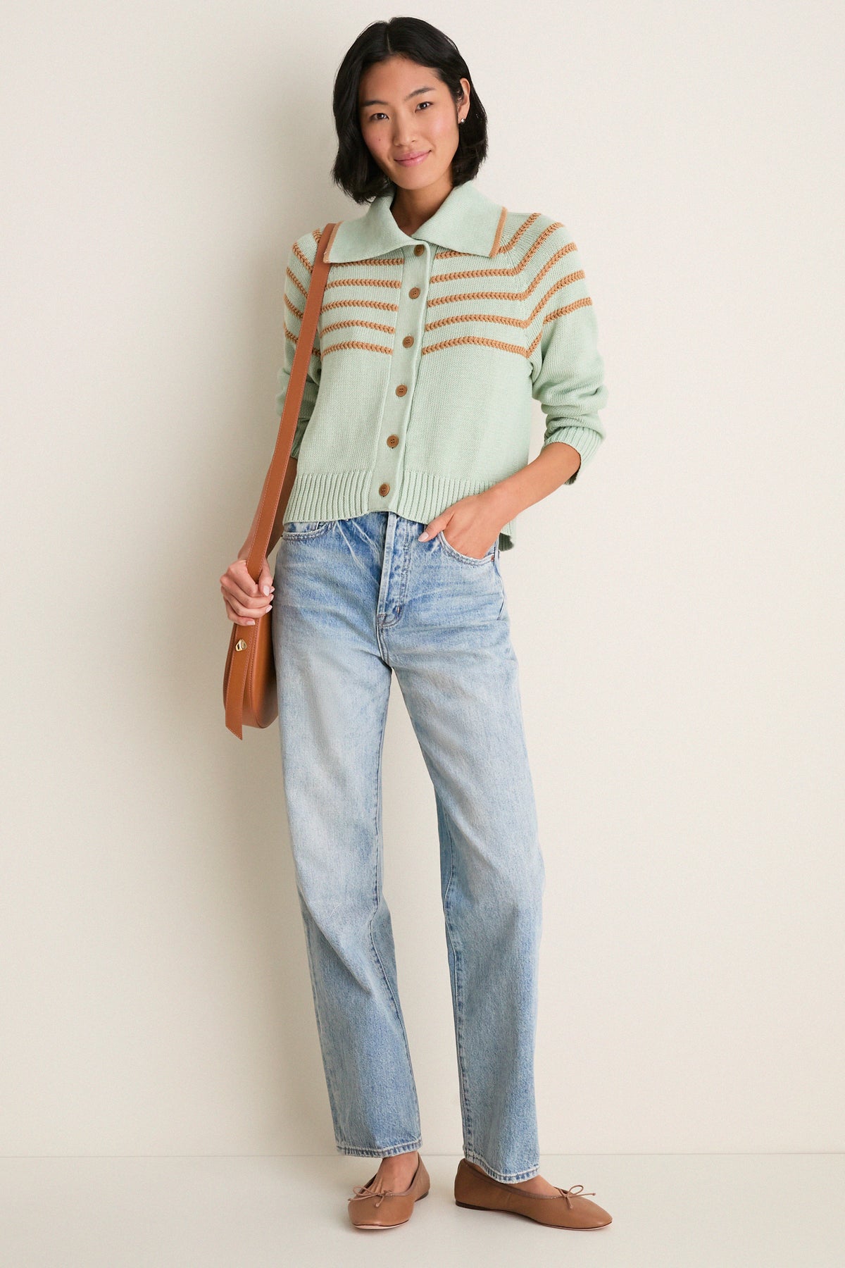 Woman in Seafoam Scholar Cardigan with Crochet Stripes, buttoned, paired with light-wash jeans, modeling a classic, high-end, effortless look with fun, relaxed elegance.