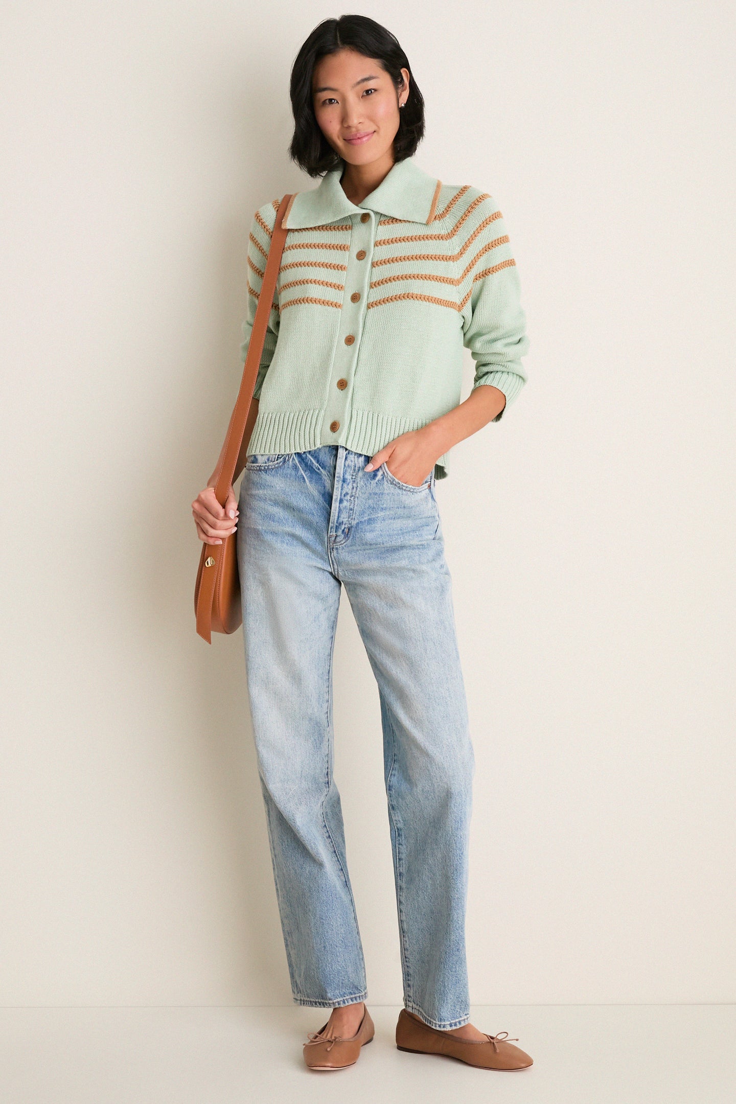 Woman in Seafoam Scholar Cardigan with Crochet Stripes, buttoned, paired with light-wash jeans, modeling a classic, high-end, effortless look with fun, relaxed elegance.